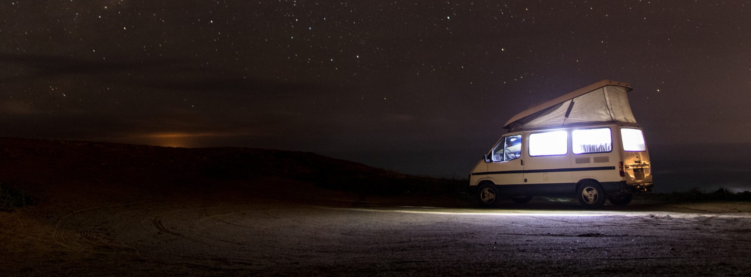 White Class B RV camping under the stars in a desert